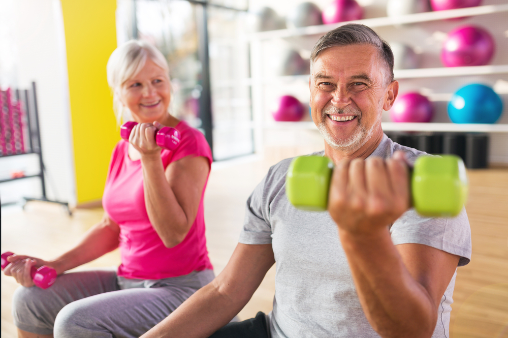 mature, happy man and woman lifting weights with exercises to reduce chronic joint pain